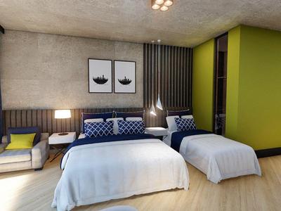 Moderne hotelkamer met twee bedden, zithoek en groene accentmuur.