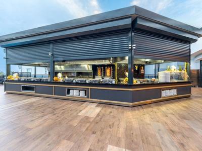 Modern open buffet in een lichte eetzaal met houten vloer en panoramische ramen.