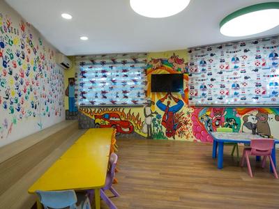 Kleurrijke speelkamer voor kinderen met tafels, stoelen en wanden vol schilderijen en tekeningen