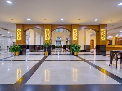 Großer heller Empfangsbereich mit poliertem Marmorfußboden, goldverzierten Säulen und modernen Möbeln.