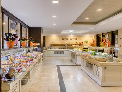 Großes Buffet mit vielfältigen Speisen, modernen Lampen und hellem Holzinterieur in hellem Raum.