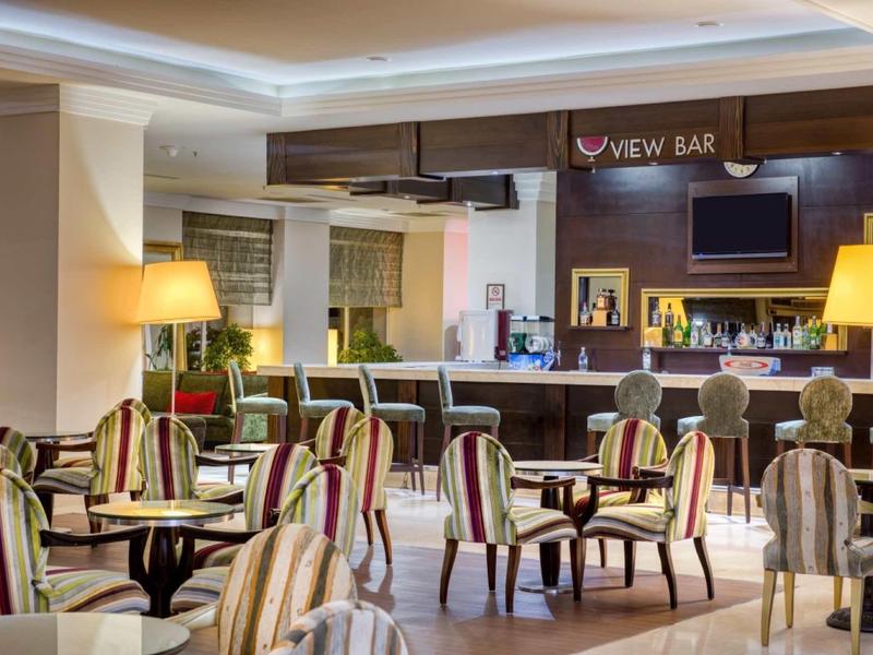 Gemütliche Bar mit gestreiften Sesseln, Tischen, Lampen und einer Theke im Hintergrund.