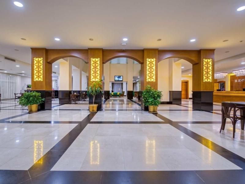 Großer heller Empfangsbereich mit poliertem Marmorfußboden, goldverzierten Säulen und modernen Möbeln.