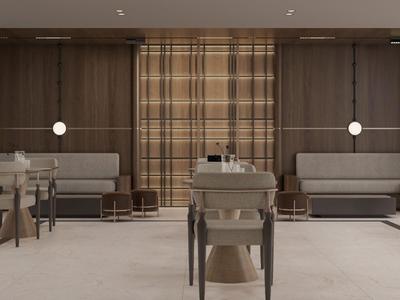 Area lounge di un hotel moderno con sedute beige, tavoli in legno e illuminazione calda.
