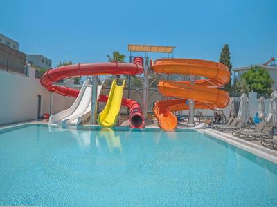 Children's water slides in multiple colors next to a clear pool under a blue sky.