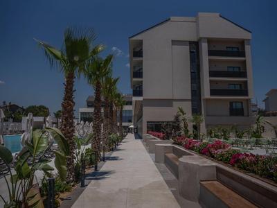Modern hotel complex with palm trees and manicured garden under clear sky.
