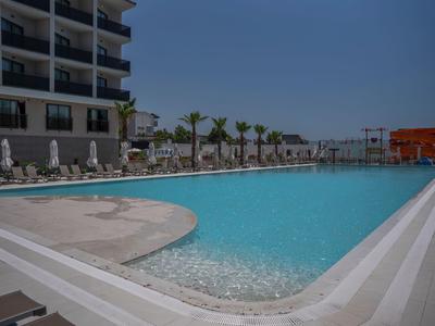 Large hotel pool with sun loungers and palm trees on a clear, sunny day.