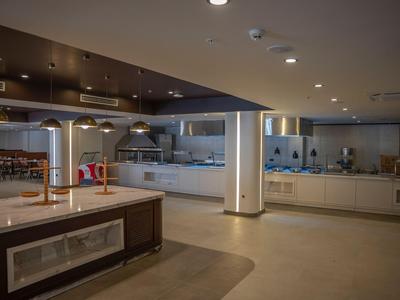 Modern hotel kitchen with stainless steel appliances, open workspace, and subdued lighting.