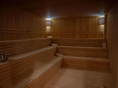 Interior of a sauna with tiered wooden benches and subdued lighting.