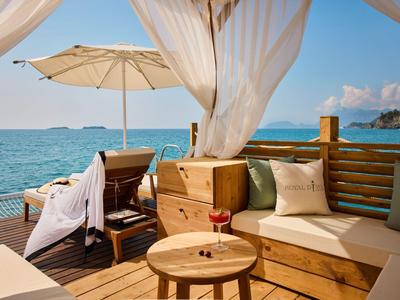 Cozy lounge with wooden furniture overlooking the sea under a blue sky.