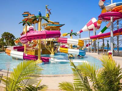 Colorful water slide park with pool and palm trees under clear blue sky.
