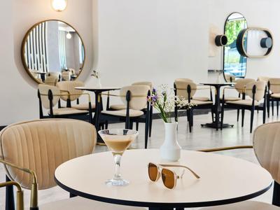 Modern bright café area with round tables, comfortable chairs, and stylish interior design.