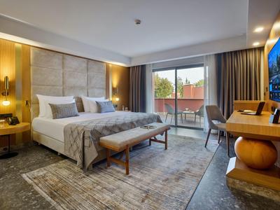 Modernes Hotelzimmer mit Doppelbett, Balkon, warmen Holzakzenten und gemütlicher Beleuchtung.