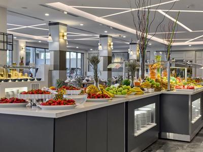 Großes Buffet mit buntem Obst, Gemüse und Salaten in modernem, hell erleuchtetem Raum.