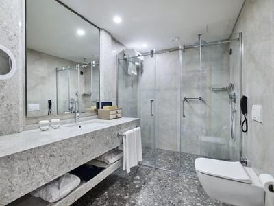 Moderner, grauer Marmor-Badezimmer mit ebenerdiger Dusche, großem Spiegel und wandhängendem WC.