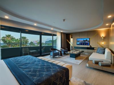 Helles, modernes Hotelzimmer mit Balkon, Panoramafenstern, Doppelbett, Sofa und stimmungsvollem Licht.