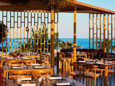 Leeres Restaurant mit Holztischen und Stühlen, offen, Blick aufs Meer und blauer Himmel.
