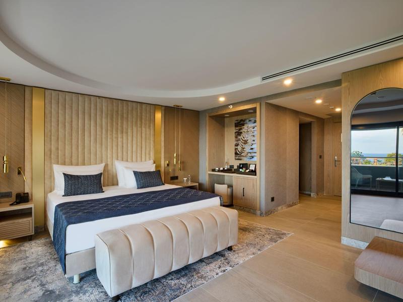 Modernes Schlafzimmer mit großem Bett, gepolsterter Bank, Teppich und Panoramafenster.