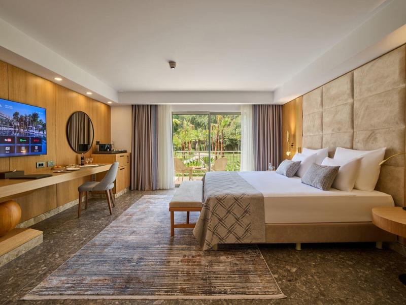 Modern eingerichtetes Schlafzimmer mit großem Bett, Holzdetails und Blick auf Garten durch Glasfenster.