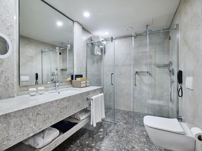 Moderner, grauer Marmor-Badezimmer mit ebenerdiger Dusche, großem Spiegel und wandhängendem WC.