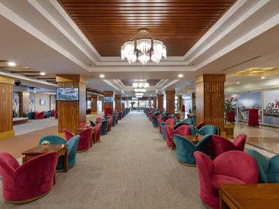 Großer Hotel-Lobby-Bereich mit Teppichboden, bunten Sesseln und Holzsäulen.