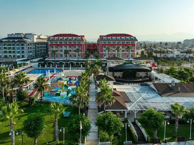 Großes Hotelresort mit Pool, Wasserpark und Palmen unter klarem Himmel.