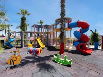 Kinderspielplatz mit Rutschen und Frühling-Schaukeln in einem Hotelaußenbereich.