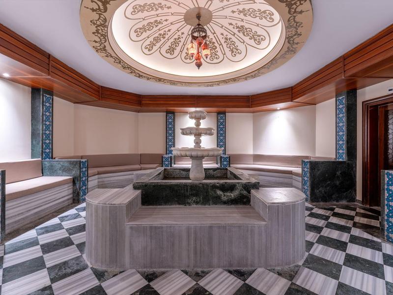 Área de espera elegante con sofás grises y decoraciones artísticas en el techo de un hotel.