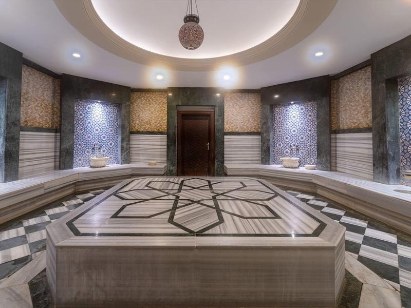 Hammam turco tradicional con piedra central y detallados mosaicos de azulejos.