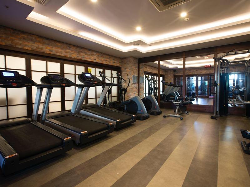 Gimnasio moderno con cintas de correr, equipos y iluminación tenue para huéspedes del hotel.