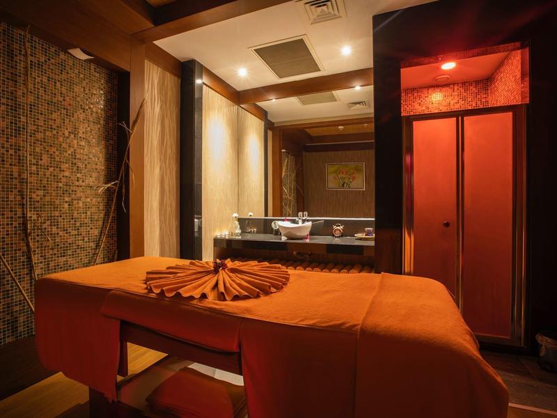 Sala de masajes acogedora con luz cálida y camilla naranja en un hotel de bienestar.