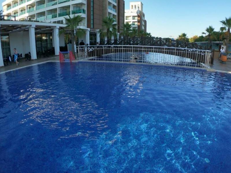 Niebieski basen przed nowoczesnym hotelem pod jasnym niebem.