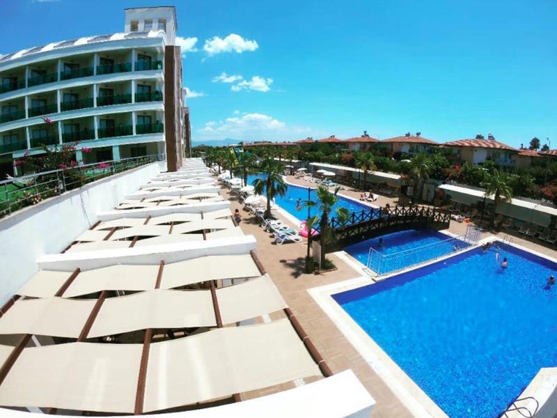 Hotel z kilkoma odkrytymi basenami otoczonymi białymi parasolami.