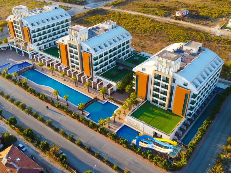 Nowoczesny kompleks hotelowy z trzema dużymi budynkami i basenami na zewnątrz.