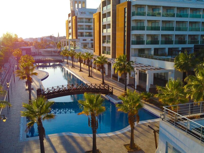 Nowoczesny hotel z basenem i palmami o zachodzie słońca.