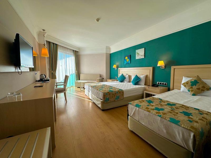 Jasny pokój hotelowy z dużym łóżkiem, pojedynczym łóżkiem, biurkiem i dużymi oknami.