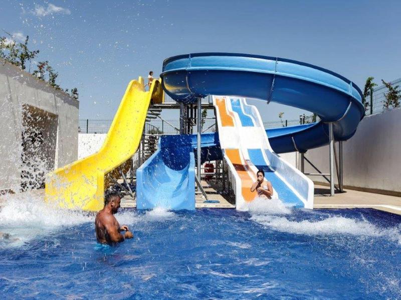 Kolorowe zjeżdżalnie wodne wpadające do niebieskiego basenu pod bezchmurnym niebem.