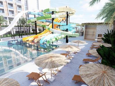 Wasserpark mit bunten Wasserrutschen neben einem Pool und Liegestühlen mit Sonnenschirmen.