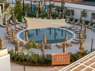 Eleganter Hotelpool mit runden Form, umgeben von Liegestühlen und Sonnenschirmen.