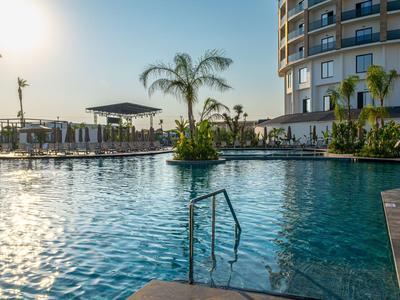 Hotelpool mit klarem blauen Wasser, Palmen und Sonnenuntergang im Hintergrund.