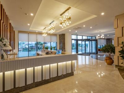 Moderne Hotellobby mit Rezeption, Beleuchtung und Sitzbereich in warmen Farben.