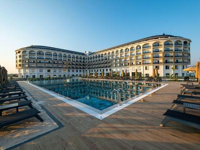 Großes Hotel mit Pool und Sonnenliegen bei Sonnenaufgang.