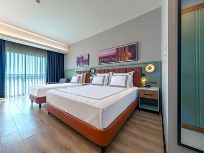 Modern eingerichtetes Hotelzimmer mit zwei großen Betten und Panoramafenstern.