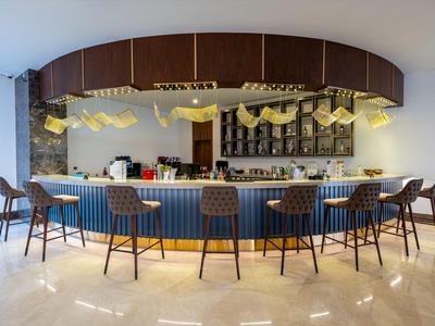 Moderne Hotelbar mit blauer Theke und acht hochwertigen Stühlen in hellem Raum.