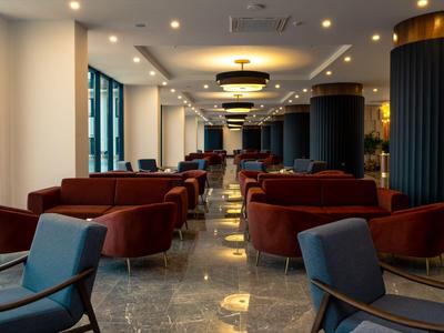 Moderner Hotel-Loungebereich mit Polstersesseln, großen Fenstern und Marmorboden.