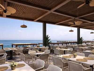 Terrazza aperta con sedie e tavoli bianchi con vista sul mare e cielo blu.