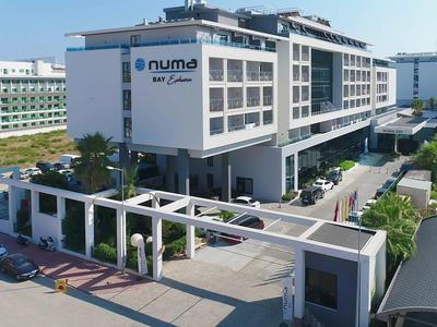 Hotel moderno de varios pisos con área de entrada y estacionamiento en clima soleado