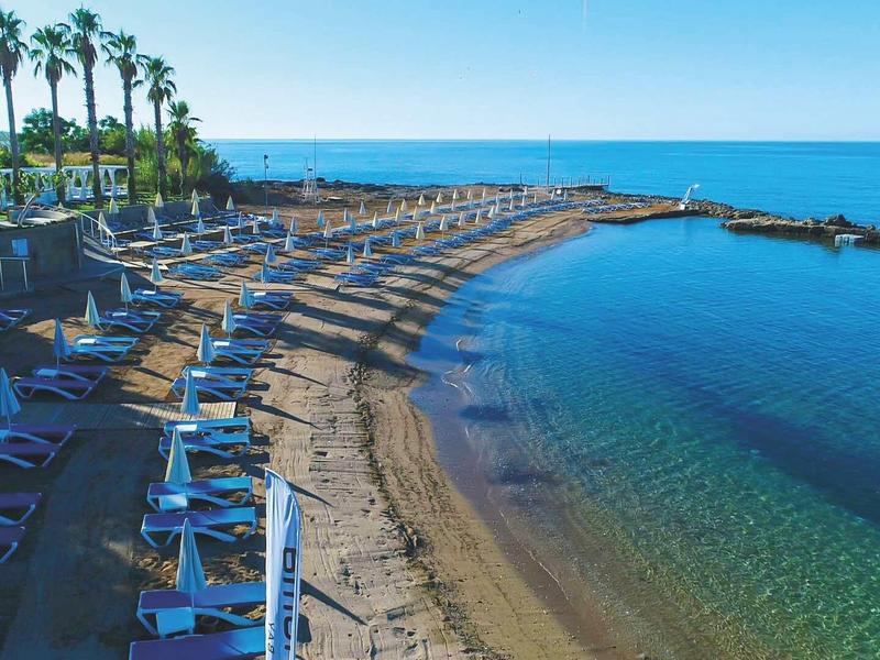 Plage avec transats, parasols et eau bleu clair à l'hôtel