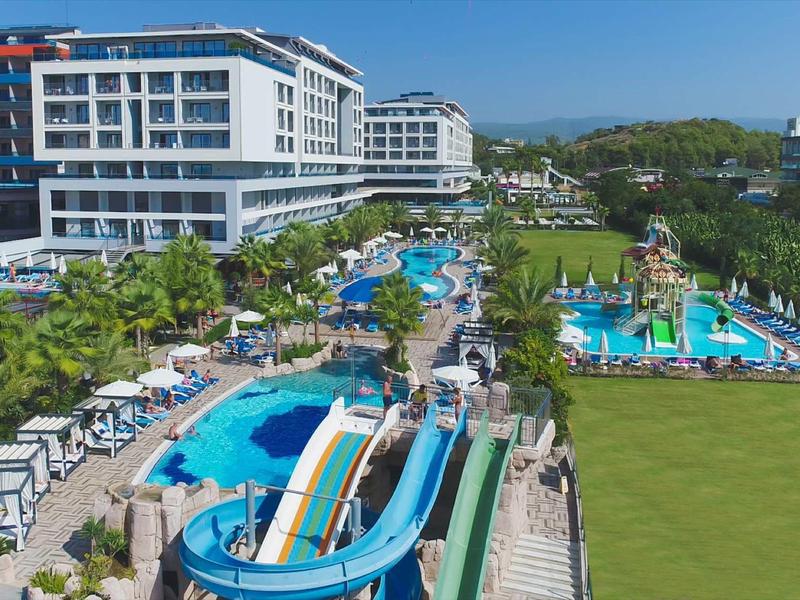 Grand hôtel avec plusieurs piscines, toboggans aquatiques et vastes pelouses vertes.