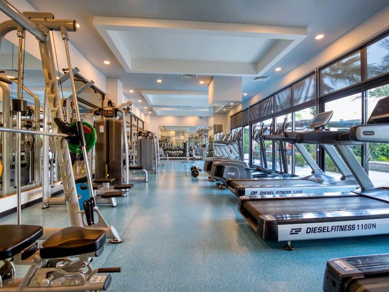 Salle de sport moderne avec équipements et tapis roulants près de grandes fenêtres